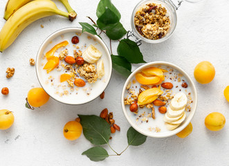Granola cereal with fruits, nuts, milk and peanut butter in bowl on a white background. Healthy breakfast cereal top view