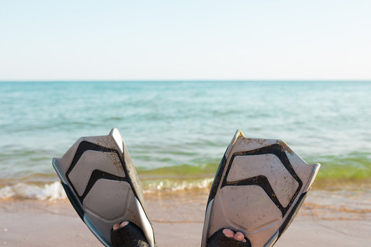 Summer wellness holidays by the sea concept, feet in fins on the beach