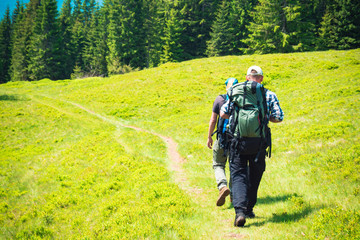 Two friends travel in the mountains with backpacks