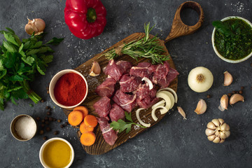Raw beef meat with ingredients for cooking healthy food. Uncooked  beef meat with herbs, spices and vegetables top view