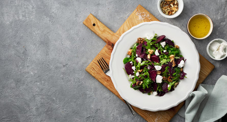 Fresh summer salad with grilled beets, feta cheese and nuts on a dark background top view