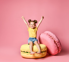 Cute little girl in bright clothes have fun at the birthday party fun room decoration candy macarons