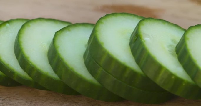 Close up pan along a row of fresh, juicy cucumber slices