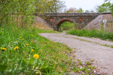 Fototapeta na wymiar An arched railway bridge over the road. Old stone viaduct.