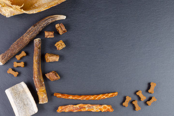 different dog food and snack, chicken filet, antlers, lung, ear on black background