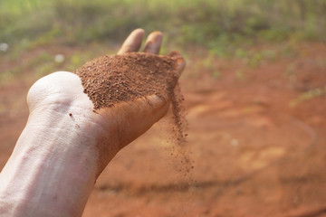 Hand man holding red soil dust on the blur background 