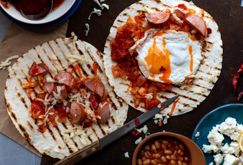 Tortilla with fried eggs, sauce and chorizo, top view, flat lay. Mexican food, beer snack.