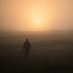Silhouette of a photographer in the fog at sunrise