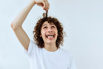 Making face,funny  foolishes portrait of Curly teen guy ,against white background.