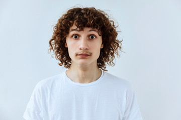 Surprised,shock ,unbelievable emotion. Curly teen guy face portrait agaist white backgraund.