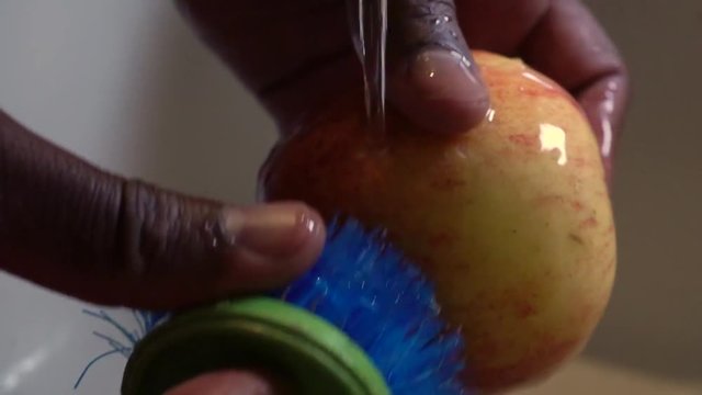 Woman rinsing apple with scrub brush, Slow Motion Close Up on Hands
