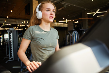 Girl in headphones running on the treadmill.