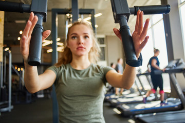 Fototapeta premium Girl in sportswear trains with gym equipment.