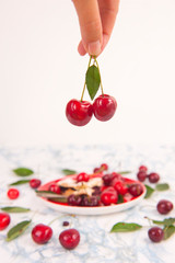 Cherry pie in the shape of a heart with fresh red cherries on the white marble table.