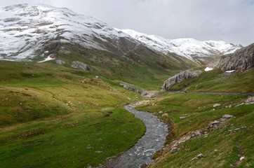Fototapeta na wymiar Stream flowing at the feet of snowy mountains