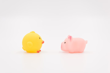  A yellow chicken toy and a pink pig toy are placed face to face, animal dialogue scene background