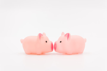 A pair of pink rubber toy pigs kissing intimately.