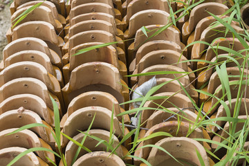 Obraz premium Stacks of yellow ceramic glazed curved roof tiles in a symmetrical pattern.