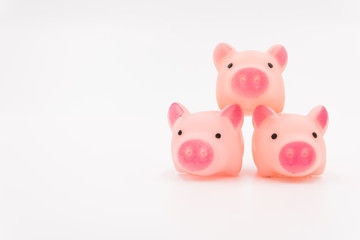 Three pink cute toy piglets stacked on the right side of the white background