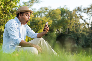 Fototapeta premium Asian man using smartphone in park