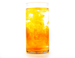 Orange food coloring diffuse in water inside tall glass with empty copyspace area for slogan or advertising text message, over isolated white background.