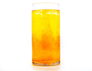 Orange food coloring diffuse in water inside tall glass with empty copyspace area for slogan or advertising text message, over isolated white background.