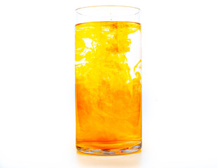 Orange food coloring diffuse in water inside tall glass with empty copyspace area for slogan or advertising text message, over isolated white background.