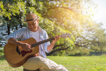 Young asian man playing guitar in park