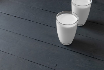 two glasses of milk on a dark wooden table