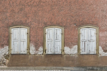 Symmetrische Fassade von verlassenem, baufälligem Haus mit 3 Fenstern mit Fensterläden