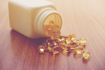 Vtamin D and Omega 3 fish oil capsules supplement on wooden table.