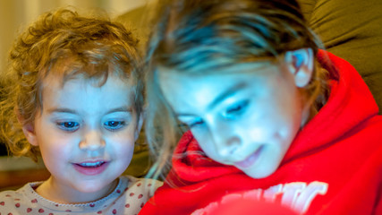 Two young girls watching a movie on their tablet screen