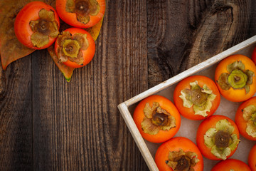 Ripe orange persimmon fruit on brown wooden table. Organic persimmon fruit  at market. Persimmons background with copy space, text place 