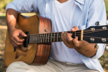 Fototapeta premium Young asian man playing guitar in park