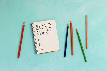 2020 year goals written in a notebook on blue background - New Year goal concept