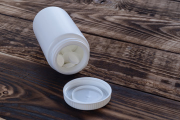 Fototapeta na wymiar Drugs in a white bottle on a wood background