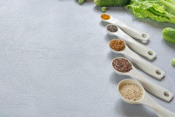 Fototapeta na wymiar Natural food additives, spices in spoons: sesame, flax seed, chia, turmeric on gray background. The concept of healthy food.