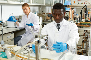Male lab technicians with different glass tubes, girl on background