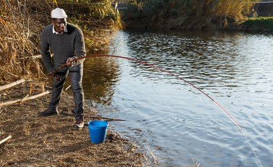 Afro fisherman pulling fish