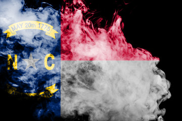 The national flag of the US state North Carolina in against a gray smoke on the day of independence in different colors of blue red and yellow. Political and religious disputes, customs and delivery.