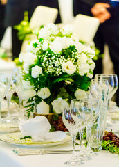 Luxury party dinner table setting with tableware and silverware and glasses set and Candlestick and flower in restaurant.