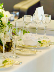 Luxury party dinner table setting with tableware and silverware and glasses set and Candlestick and flower in restaurant.