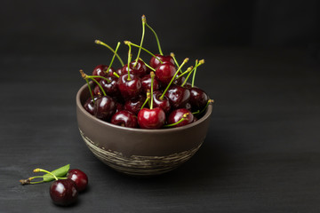 Fresh sweet cherries bowl on black background. Healthy food concept, plant background, natural eco-products, organic food, vegetarian, raw, festival food, art