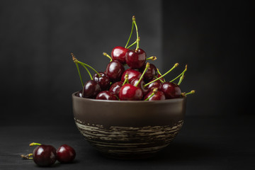 Fresh sweet cherries bowl on black background. Healthy food concept, plant background, natural eco-products, organic food, vegetarian, raw, festival food, art