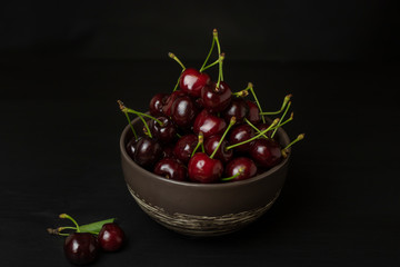 Fresh sweet cherries bowl on black background. Healthy food concept, plant background, natural eco-products, organic food, vegetarian, raw, festival food, art