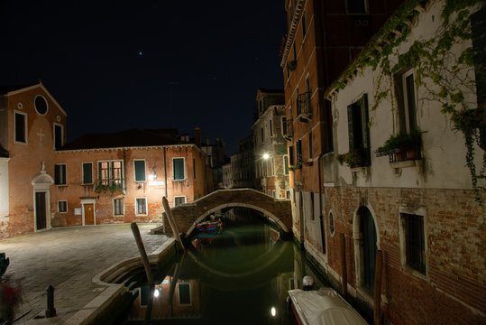 Night photograph of the Ruga Vecchia bridge in Campo San Giacomo dell'Orio in the Santa Croce district in Venice, Italy. Typical old Venetian houses with facade on the bridge and on the canal. streets