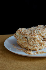 Photo of a delicious fantastic homemade fresh layered honeycomb modern cake on a porcelain white plate on wooden table and  black background indoor  rustic style