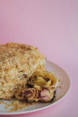 Photo of a delicious fantastic homemade fresh layered honeycomb modern cake on a porcelain white plate on pink background indoor on sunlight rustic style