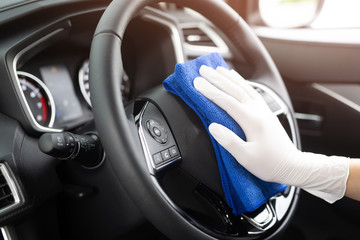 Obraz na płótnie Canvas A worker hand wear glove cleaning car console steering wheel with microfiber cloth, car wash detailing concept. 