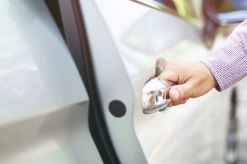 Obraz premium Close up image of a businessman hand on handle opening a car door. Pull the door to you.